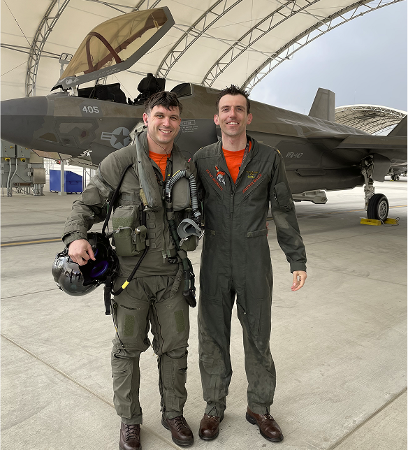 Two pilots in military flight suits standing in front of an F-35 fighter jet